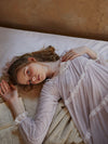 Woman lying on bed wearing vintage-inspired lace nightdress