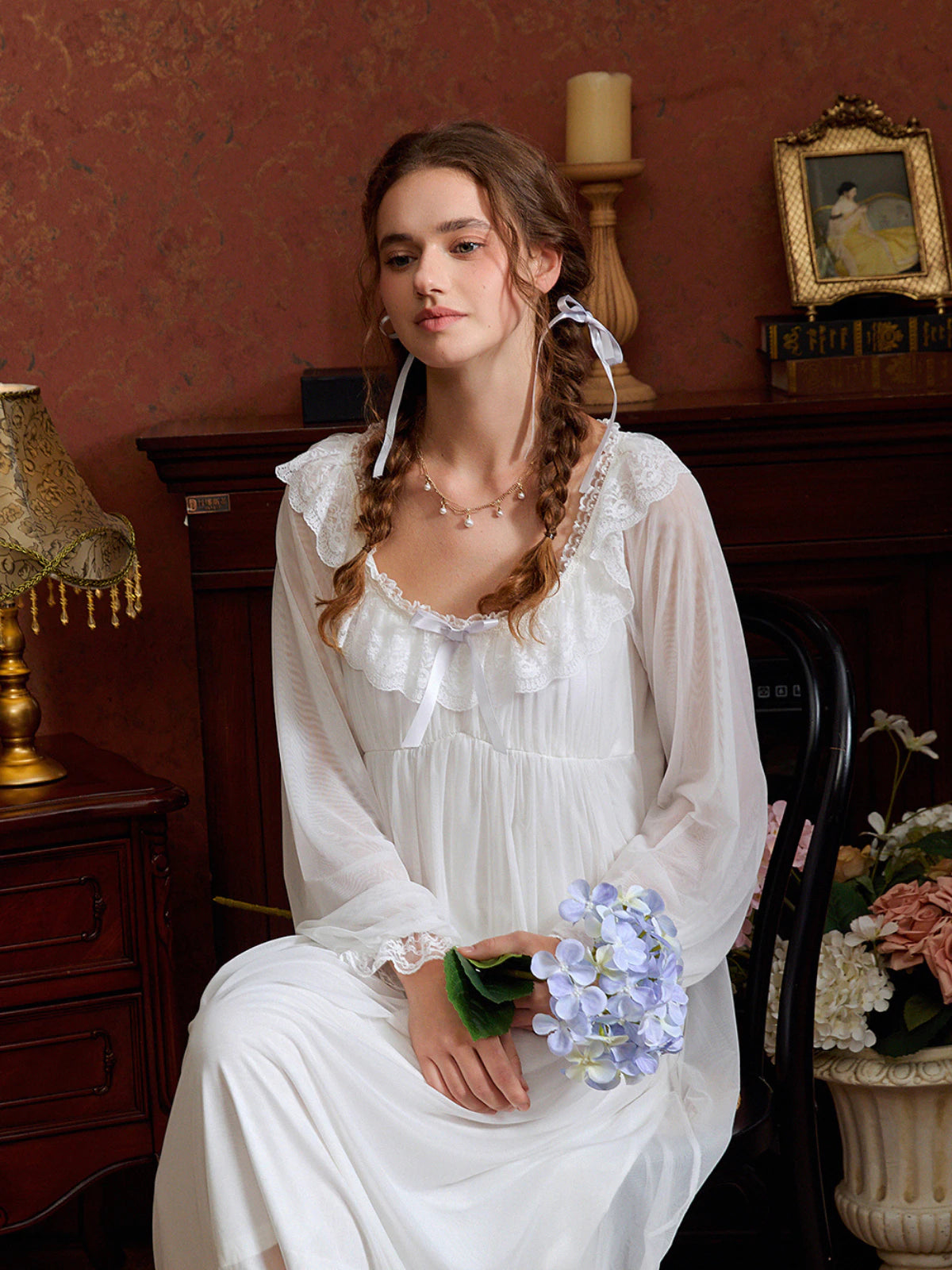 Seated view of the white lace nightgown showing translucent sleeves and softly gathered skirt layers