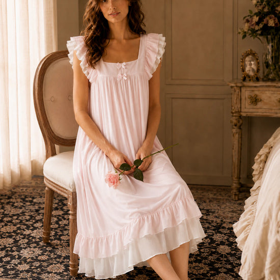 Woman sitting in SlesSic blush pink lounge dress with romantic soft girl styling