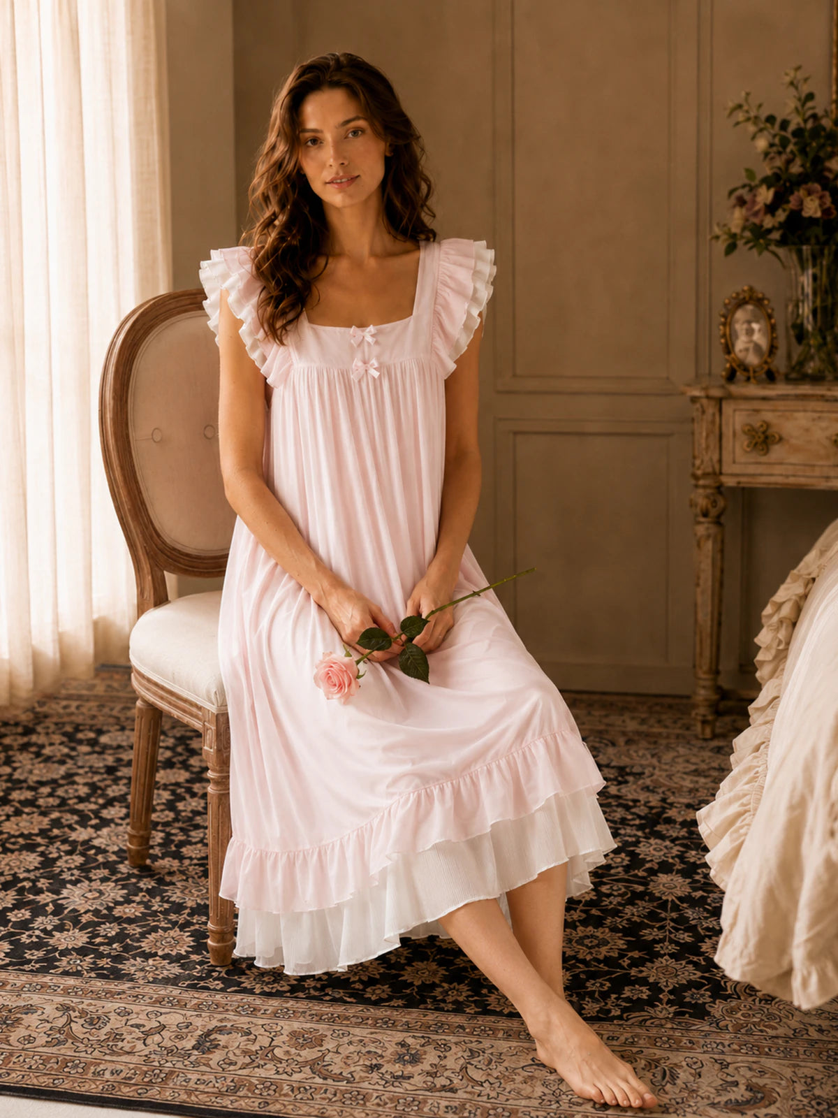Woman sitting in SlesSic blush pink lounge dress with romantic soft girl styling