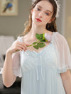 Close-up of light blue lace neckline, bow, and sheer sleeves