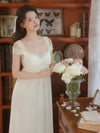 Woman wearing soft light yellow vintage nightdress with lace details beside roses