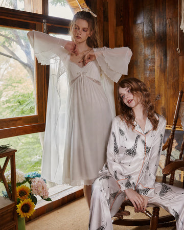 SlesSic romantic sleepwear collection featuring a white lace nightgown and silky printed satin pajamas in a warm vintage-inspired interior.
