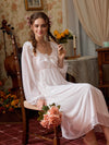 Seated view of the pink lace nightgown showing its sheer sleeves, soft lining, and romantic drape