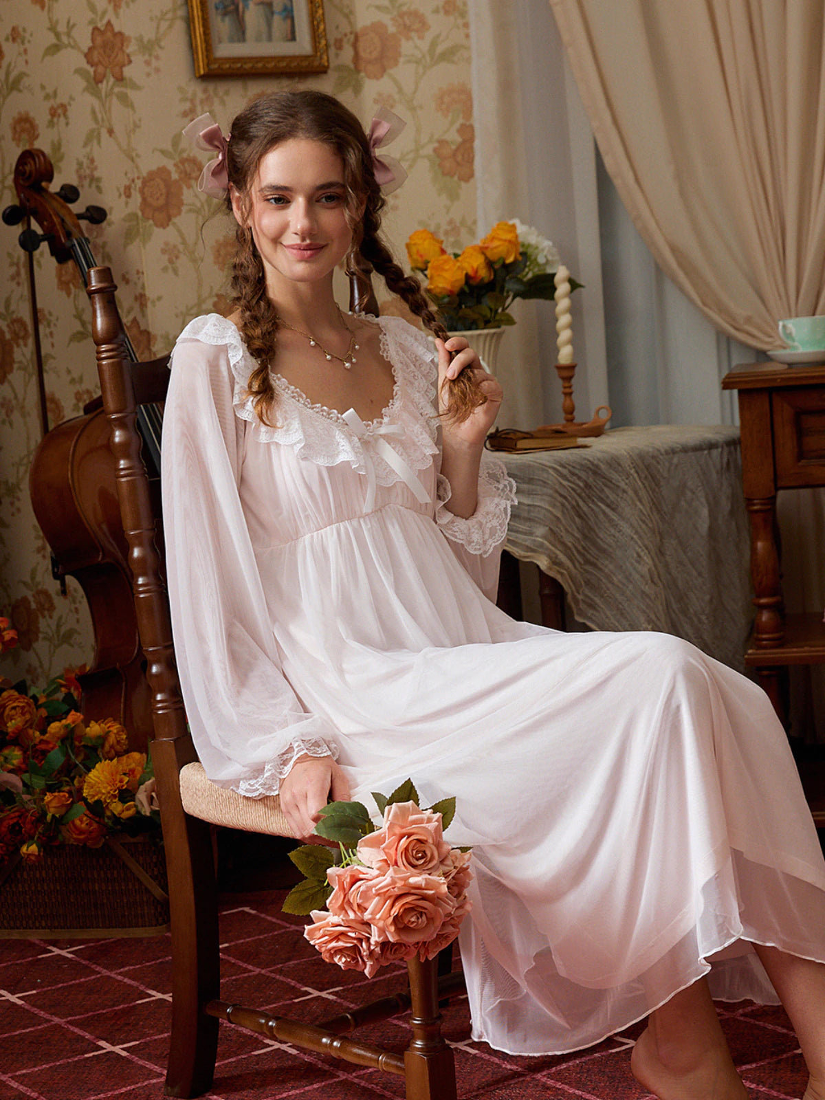 Seated view of the pink lace nightgown showing its sheer sleeves, soft lining, and romantic drape