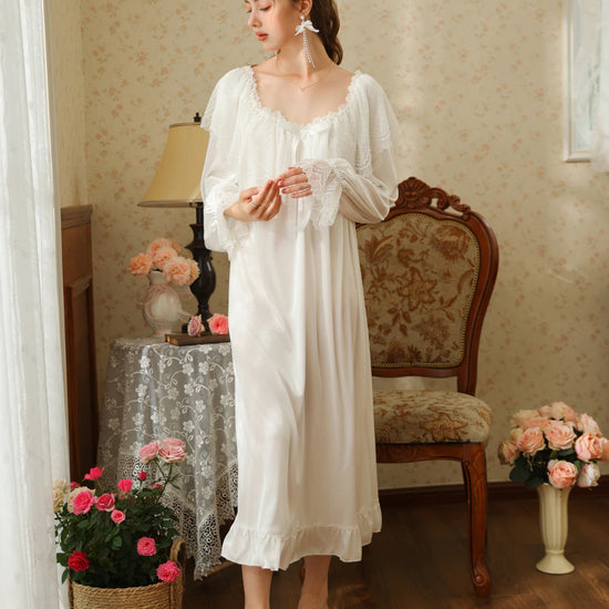 Standing front view of the white nightgown showing its long flowing shape, gathered lace neckline, and ruffle hem