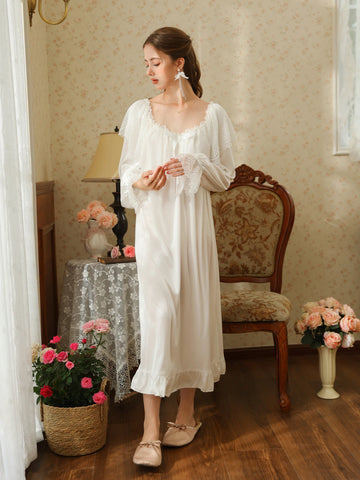 Standing front view of the white nightgown showing its long flowing shape, gathered lace neckline, and ruffle hem