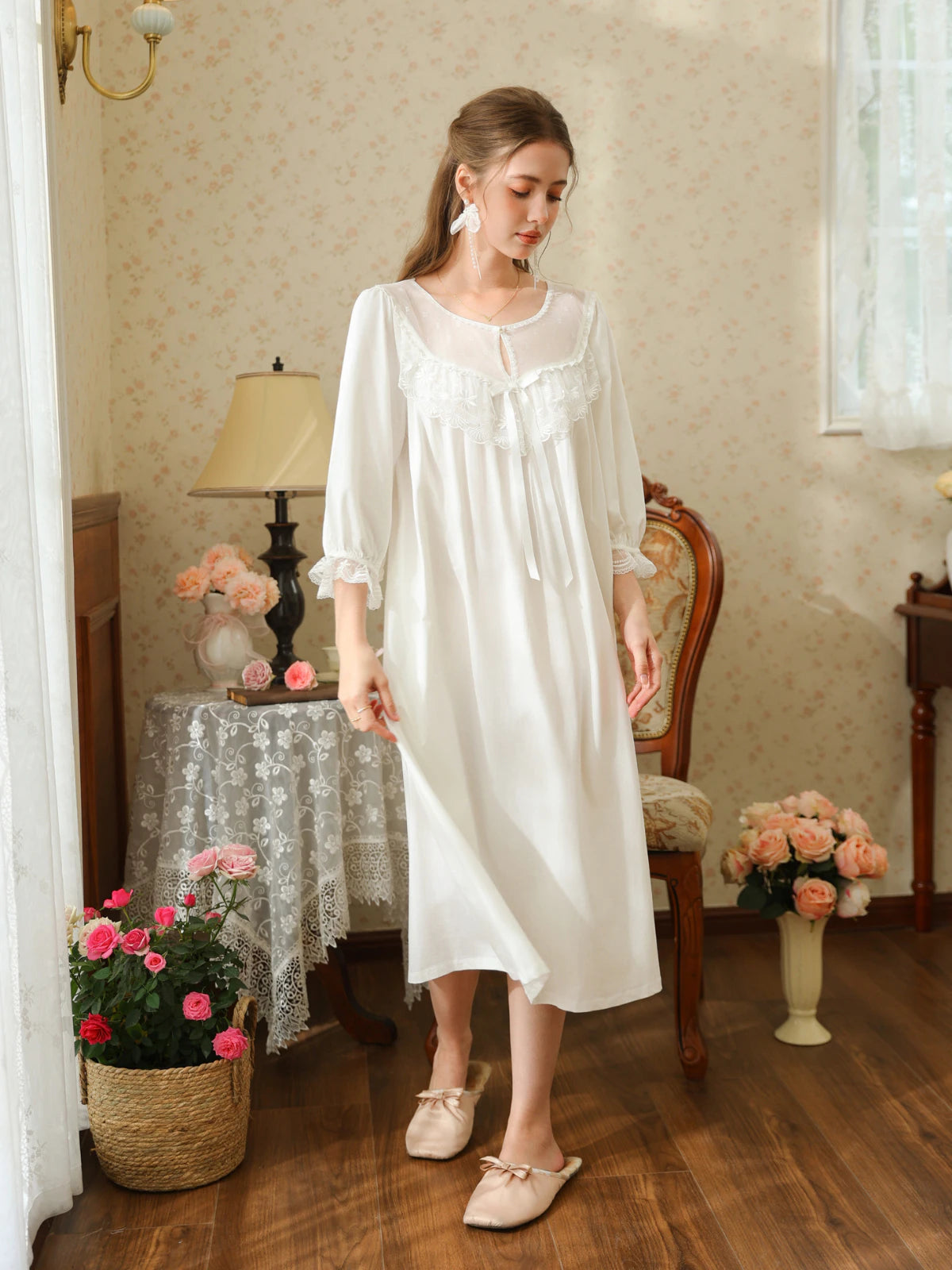 Full-length angled view of the white cotton nightgown showing the gathered sleeves, scalloped cuffs, and flowing midi silhouette