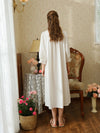 Back view of the white cotton nightgown showing the gathered back yoke, relaxed skirt, and lace trimmed sleeve cuffs