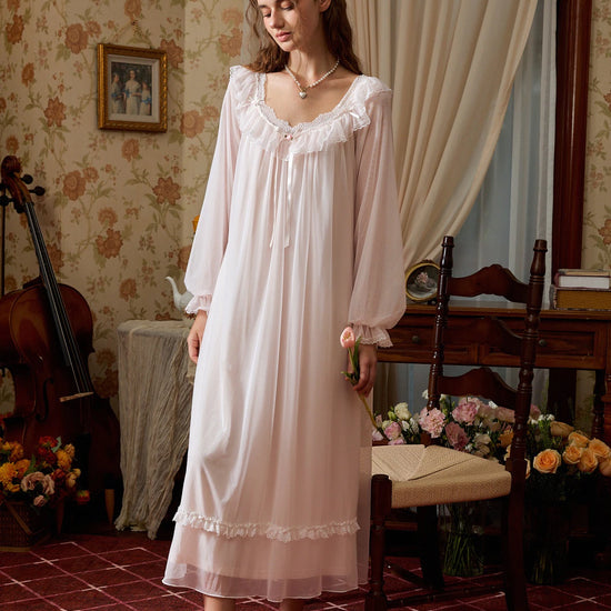 Full-length light pink nightgown with long sheer sleeves and a floral lace band above the translucent hem