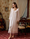 Full-length light pink nightgown with long sheer sleeves and a floral lace band above the translucent hem