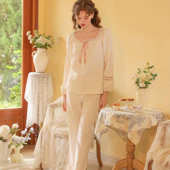 Seated view of the white pajama set highlighting the satin bow and floral lace sleeve panels