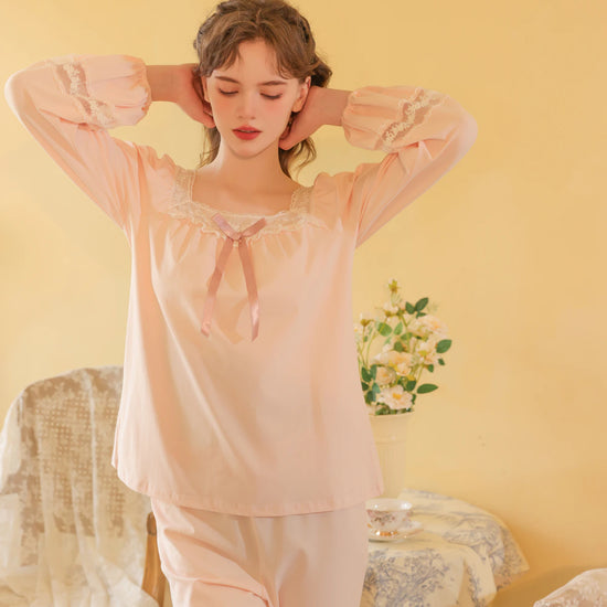 Seated view of the pink pajama set highlighting its soft drape and floral lace insets