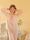 Seated view of the pink pajama set highlighting its soft drape and floral lace insets