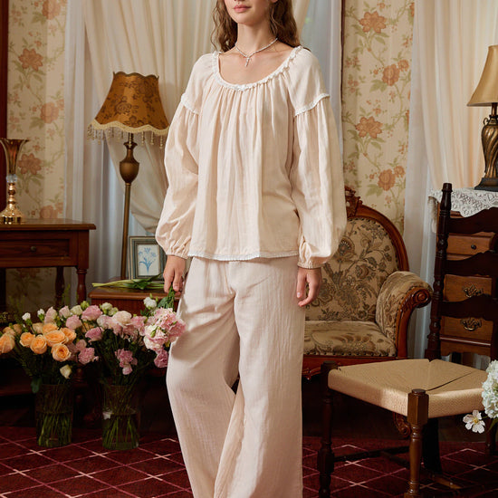 Angled front view of the light yellow cotton pajamas showing loose long sleeves, lace-trimmed hems, and wide-leg pants