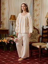 Angled front view of the light yellow cotton pajamas showing loose long sleeves, lace-trimmed hems, and wide-leg pants