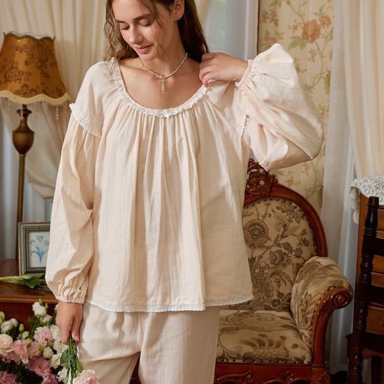 Light yellow cotton pajama top shown from the front with dropped shoulders, gathered cuffs, and scalloped lace edging