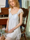 Woman wearing SlesSic lightweight lace nightgown in elegant vintage bedroom
